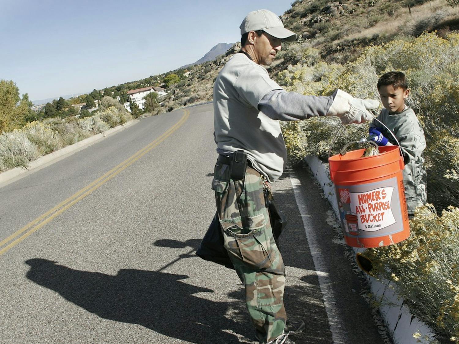	Anthony Freitas and his son, Artemas, clean up trash at Piedra Lisa Open Space Area Saturday morning. The father-son team participated in volunteering as part of national Make a Difference Day. 