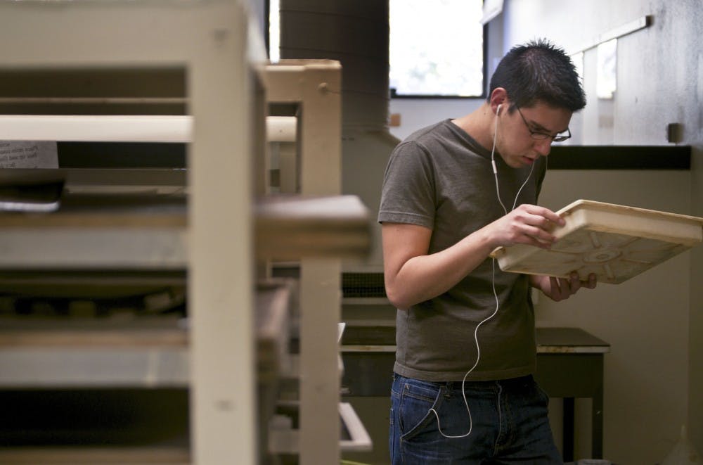 	Bret Humbard looks at his print at the photo lab Tuesday. Budget constrains are forcing the Department of Art and Art History to eliminate four classes and scale back two TA positions.