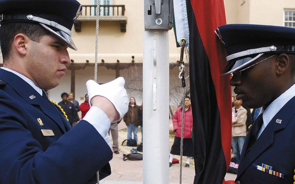 Air Force cadets Anthony Tuero, left, and Kevin Harris raise the flag of Pan-Africanism in front of Scholes Hall on Thursday to commemorate the beginning of Black History Month at UNM. 