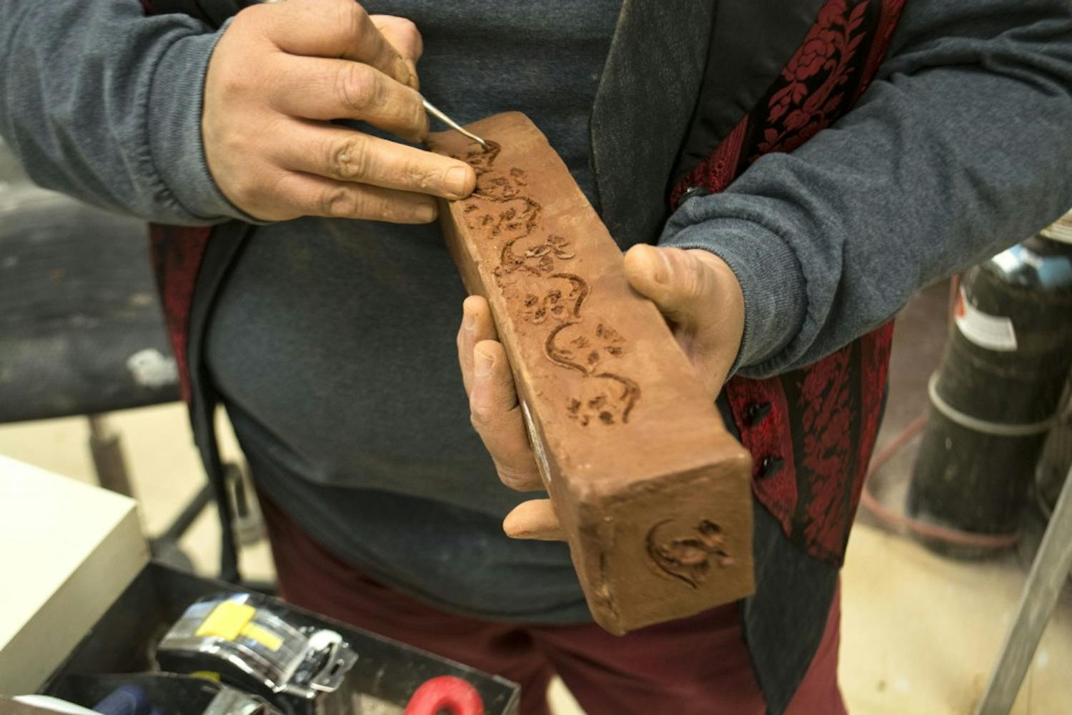 A member at the ASUNM Arts and Crafts Studio carves intricate designs into a clay object. The Arts and Crafts Studio, located in the bottom level of the SUB, offers a variety of materials for making jewelry and ceramics.
