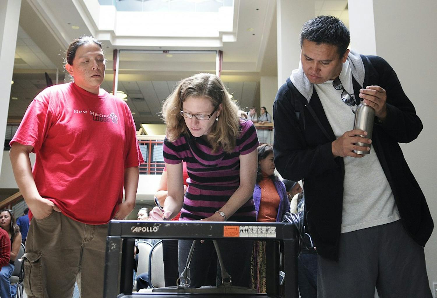 	Assistant Professor Kathleen Washburn, center, signs a petition at the SUB on Monday encouraging UNM to recognize Indigenous Day as a holiday instead of Columbus Day. Mario Atencio, left, and Russell Grey also signed the petition, which had about 60 signatures.