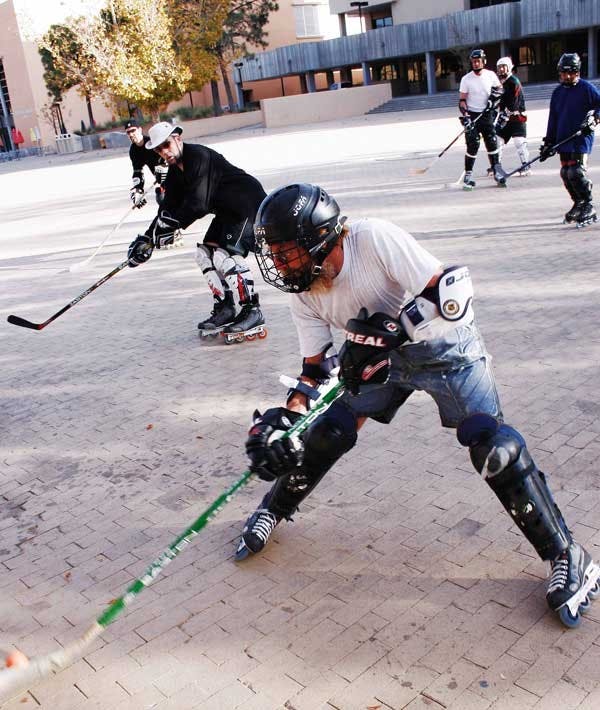 Steve Steidl, front, hits a puck during a roller hockey game Sunday in Smith Plaza. The group has played every Sunday for the past 13 years.