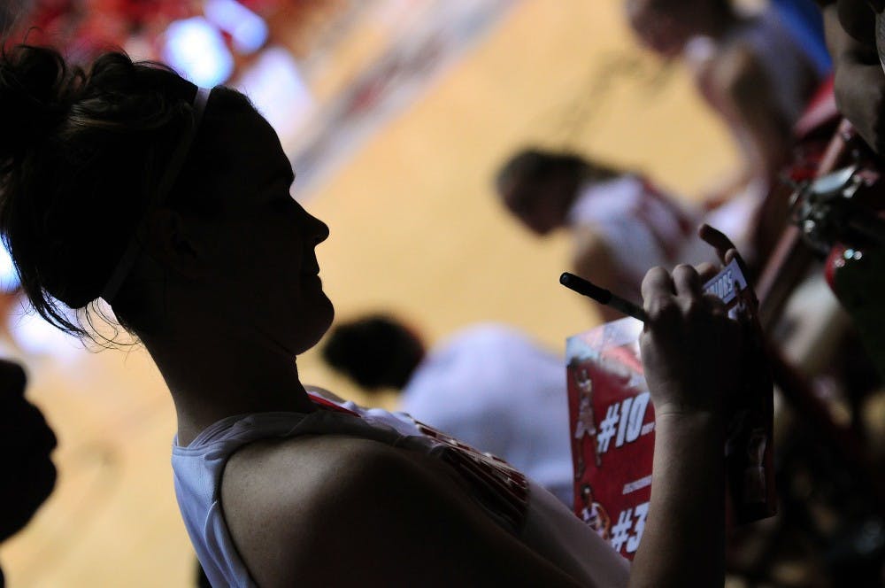 	Senior Eileen Weissmann autographs a poster for a fan after the Lobos’ 62-30 whitewash over BYU on Saturday at The Pit.