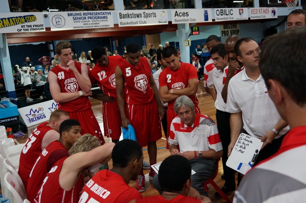	New Mexico men&#8217;s basketball coach Craig Neal, kneeling, talks with his team during a timeout during an exhibition game against the Sydney Kings, the Lobos&#8217; first game of a three-game tour in Australia. UNM won 87-85.