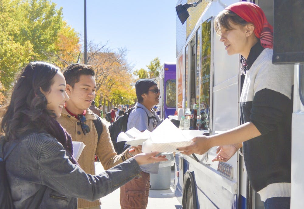 Soobak Korean Seoul Food employee Ann Atkinson, far right, hands food to UNM sophomore Jolynn Alarid, far left, and UNM senior Jabez Ledres during the Food for Thought Drive at Cornell Mall on Thursday afternoon. GPSA and UNM Foods sponsored the food drive to fund the Graduate Summer Scholarship.