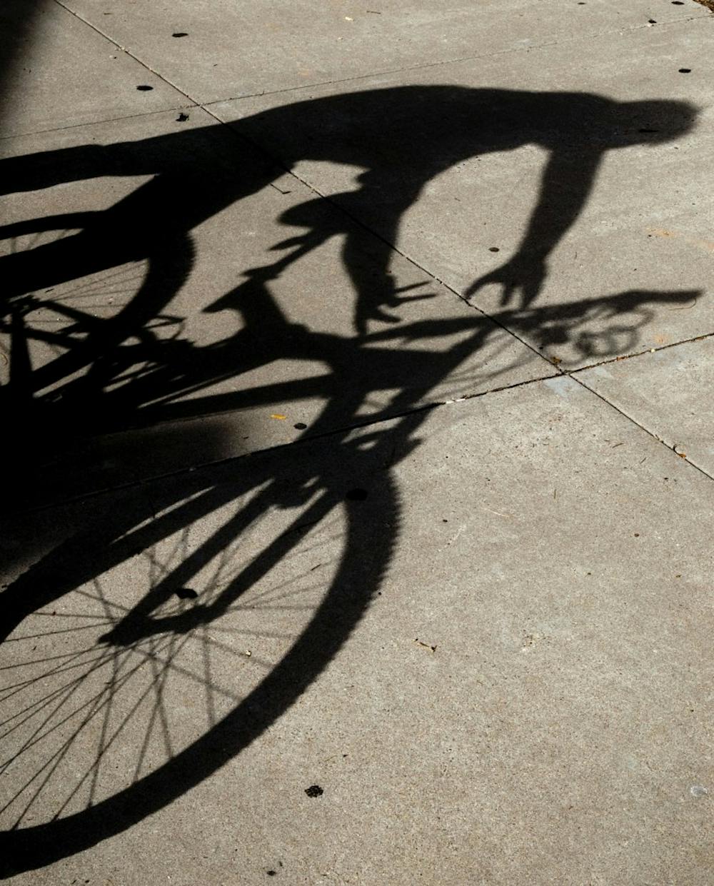 	In this photo illustration, a man attempts to steal a locked-up bicycle. Charles Gutierrez was arrested July 24 for stealing several bikes worth thousands of dollars in total from the UNM campus.