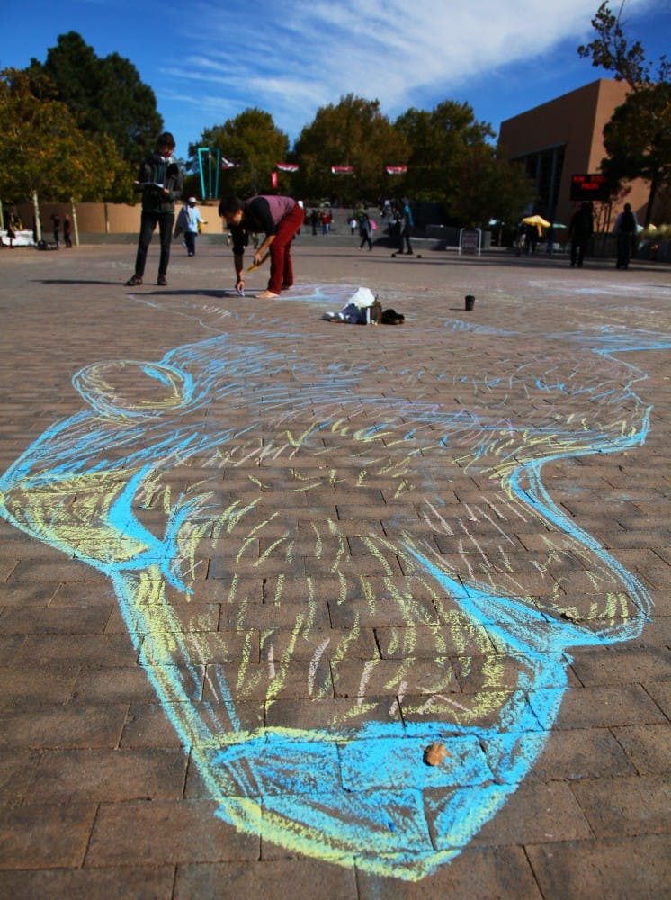 	Erika Burleigh draws a lobo at Smith Plaza on Wednesday.  Burleigh is trying to get students to sign a petition for lobo reintroduction in New Mexico.