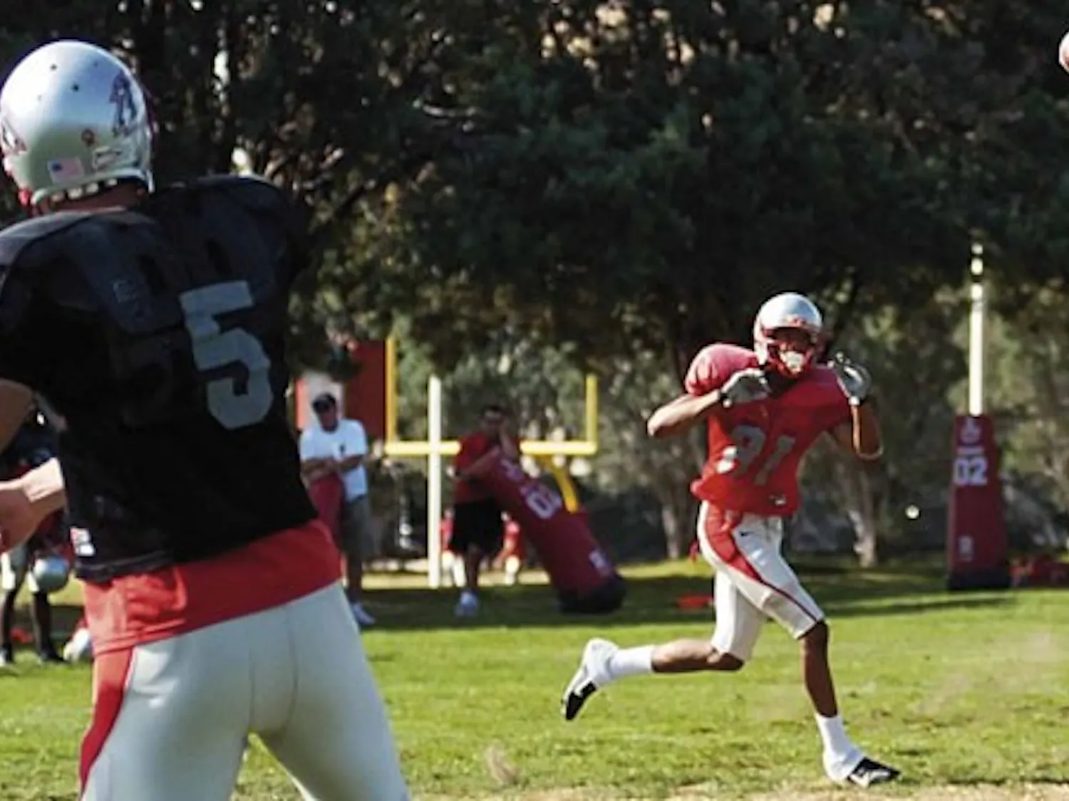 Lobo quarterback Chris Nelson throws a pass to wide receiver Travis Brown during practice Thursday at Lobo football practice field.