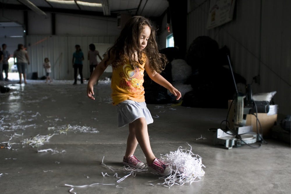 	Maya Lucero kicks around shredded paper used to stu Zozobra. The 50-foot e gy is  lled with old detention documents donated by the state government. 