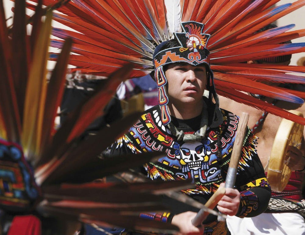 Dancer Luis Garcia performs a blessing with other Aztec dancers as part of a C