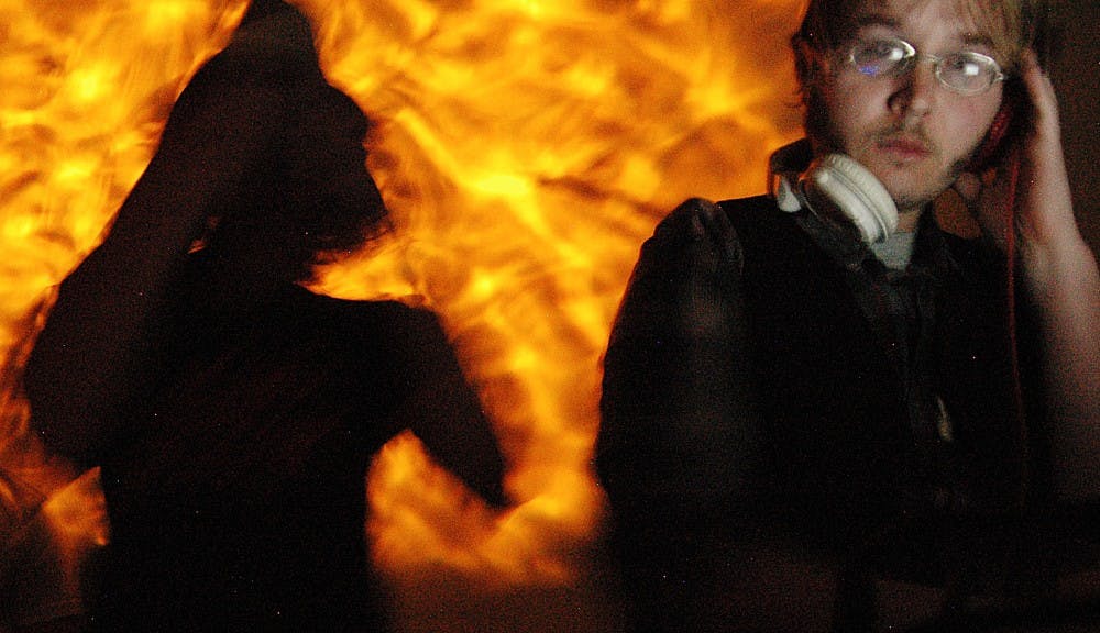 	Paul Spella mixes a song during Mustachio Bashio on Friday while a shadowy figure dances on stage during Click Click Bang’s performance at the Double Tree Hotel.      