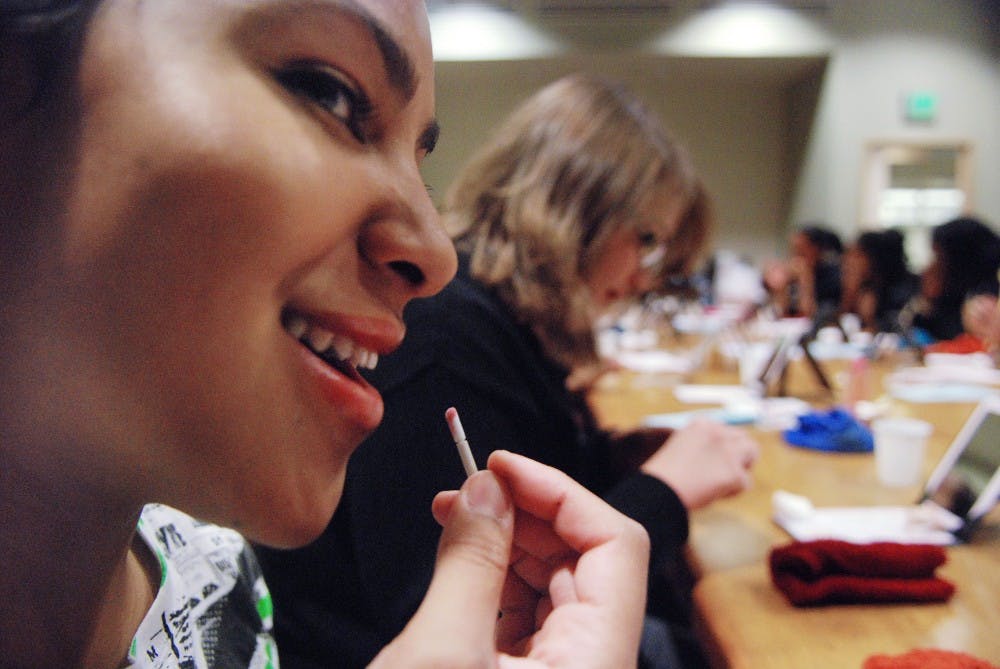 	Shay Basey, left, and Samantha Orr apply lip gloss during a free Mary Kay facial in the SUB on Thursday. Basey and Orr will dress as kings to compete in UNM’s first annual drag show and queer prom on Saturday in the SUB.