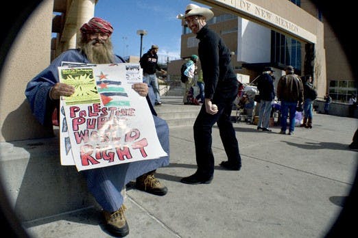 James Tiger holds a sign in support of Palestine in front of the Bookstore on Wednesday. Tiger encouraged passersby to join in a protest on March 21 that will begin at Rep. Martin Heinrich's office.