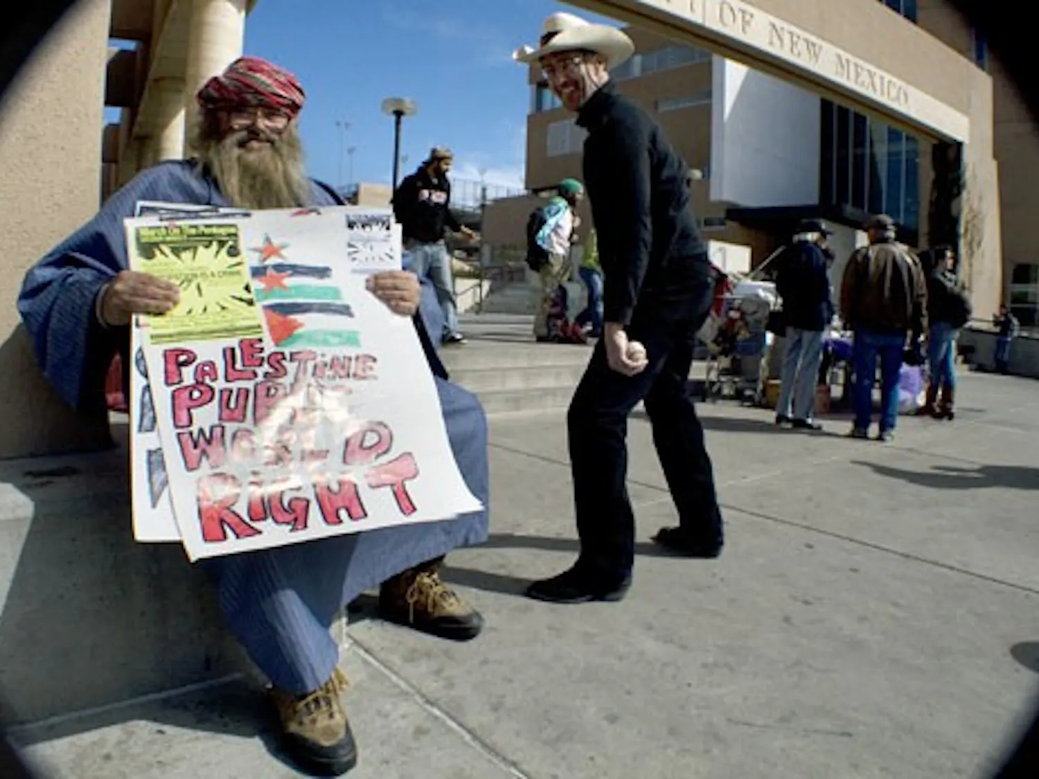 James Tiger holds a sign in support of Palestine in front of the Bookstore on Wednesday. Tiger encouraged passersby to join in a protest on March 21 that will begin at Rep. Martin Heinrich's office.