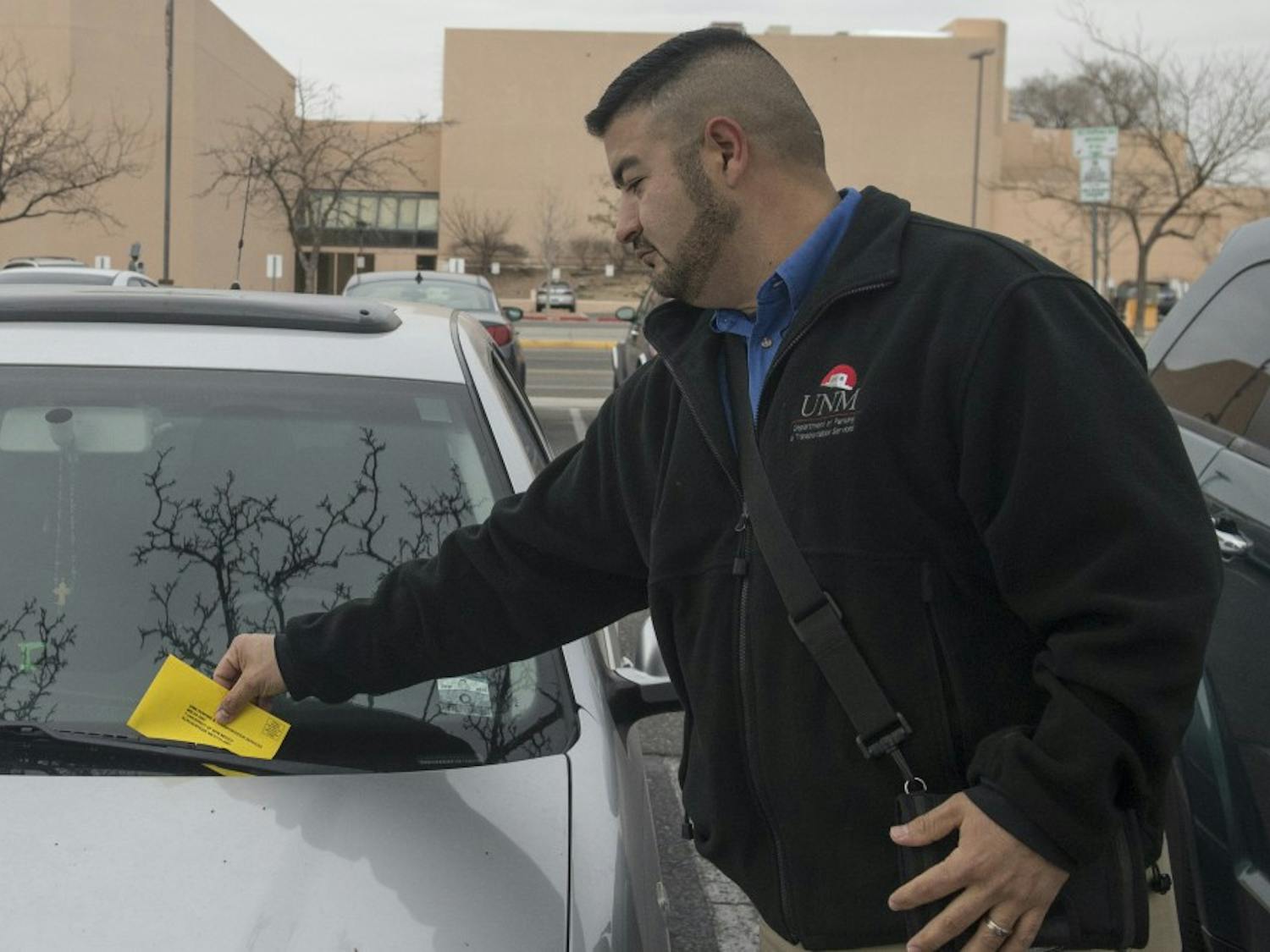 Albert Tafoya, supervisor of UNM Parking and Transportation Services, puts a parking ticket on the windshield of a car that parked without a permit at the A Lot on Monday.