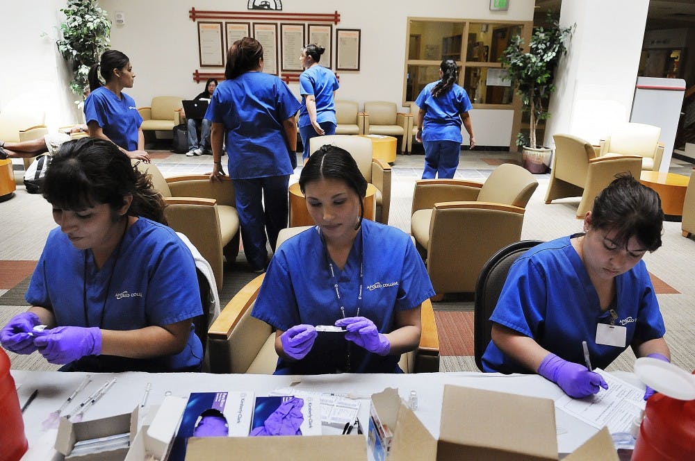 	Cindy Legarda, left, Dorian Delgaldo, center, and Stephanie Ortiz prepare flu vaccinations in the SUB atrium Monday. Congressman Martin Heinrich stopped by campus yesterday to see how well UNM was prepared for a potential H1N1-virus outbreak.