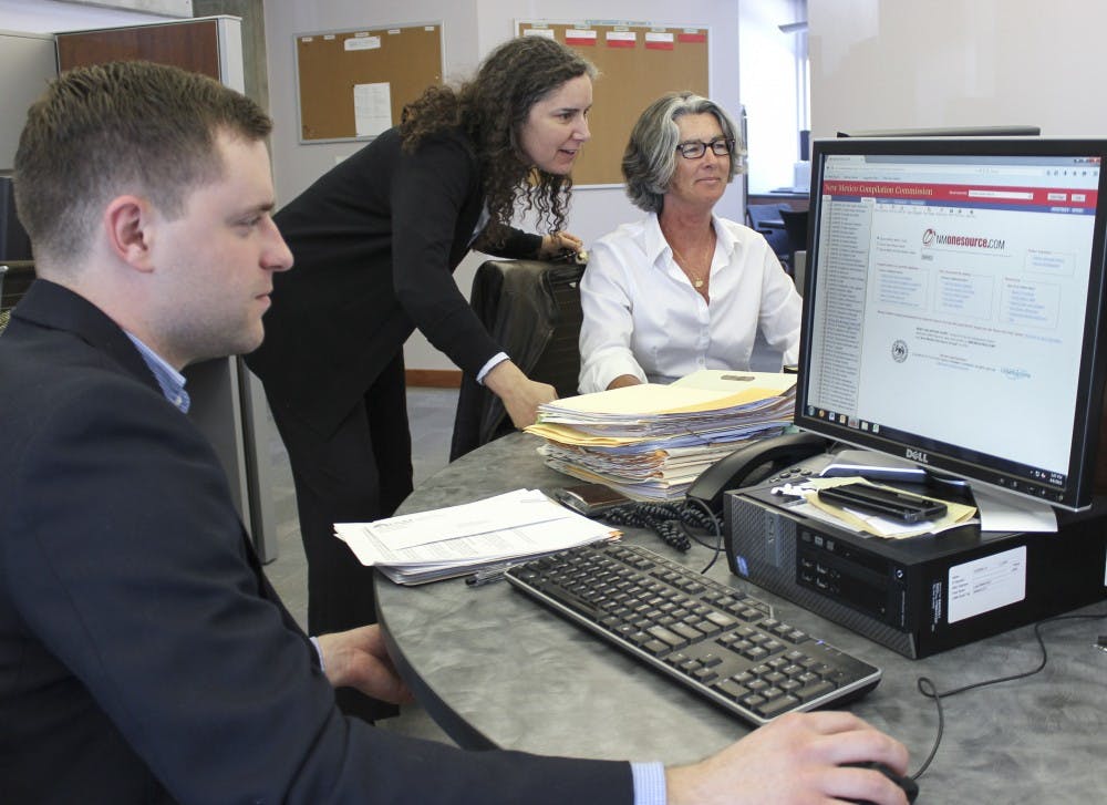 UNM Clinical Law Program director April Land, center, helps law students Daniel Dietz, left and  Lynne Canning, who work in general law in the Law Practice Clinic. UNMs School of Law has a high ranking in clinical training.