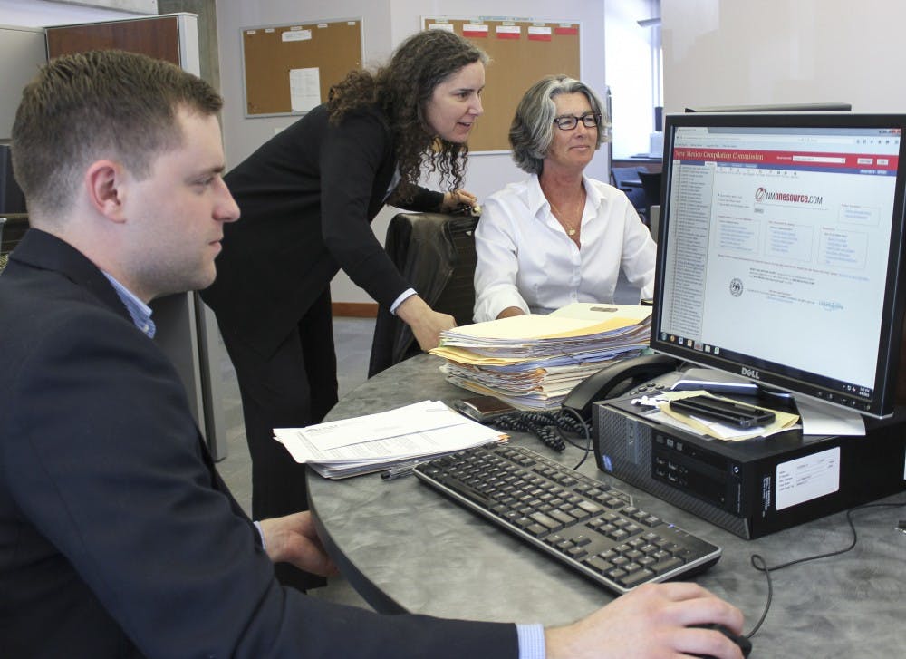 UNM Clinical Law Program director April Land, center, helps law students Daniel Dietz, left and  Lynne Canning, who work in general law in the Law Practice Clinic. UNMs School of Law has a high ranking in clinical training.
