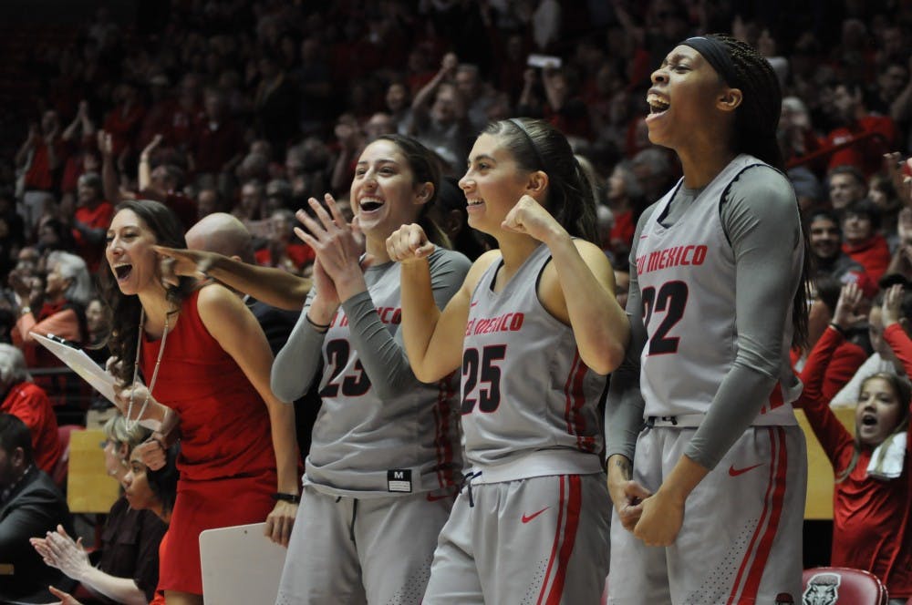 (From right to left) Antonia Anderson, No. 32, Laneah Bryan, No. 25, Jaeydn De La Cerda, No. 23, and Director of Operations Vera Jo Bustos celebrate following a made 3-pointer by Alex Lapeyrolerie during overtime against the Naval Academy on Dec. 10, 2017. The Lobos used a strong overtime period to win 94-87.