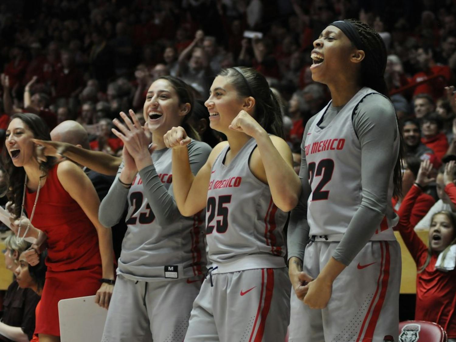 (From right to left) Antonia Anderson, No. 32, Laneah Bryan, No. 25, Jaeydn De La Cerda, No. 23, and Director of Operations Vera Jo Bustos celebrate following a made 3-pointer by Alex Lapeyrolerie during overtime against the Naval Academy on Dec. 10, 2017. The Lobos used a strong overtime period to win 94-87.