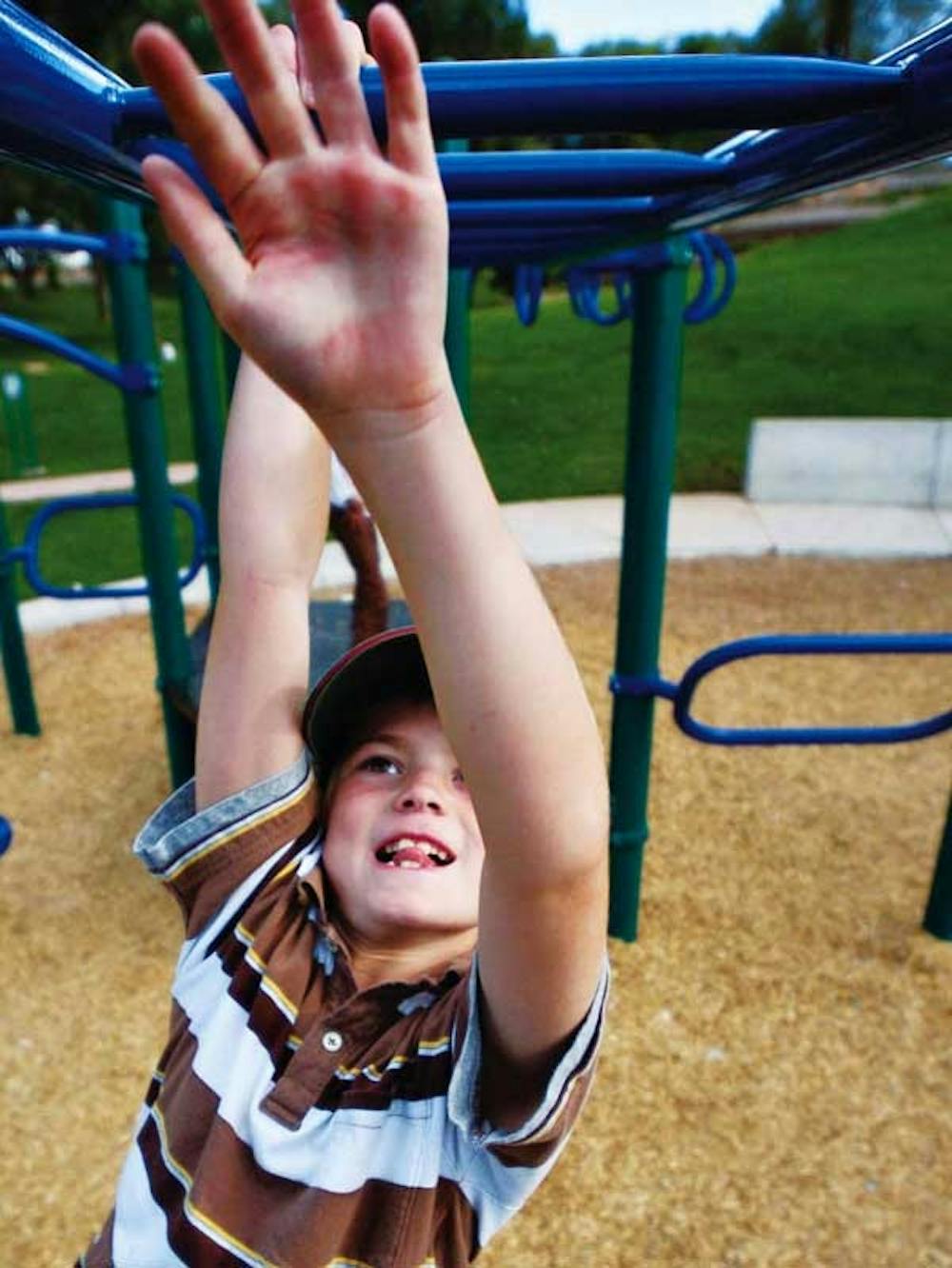 Cooper Munger, 7, climbs across the monkey bars at the Roosevelt Park playground on Thursday. His mother, Carrie, said, "I've never had a problem here, but I keep my guard up because of the history of the area."  