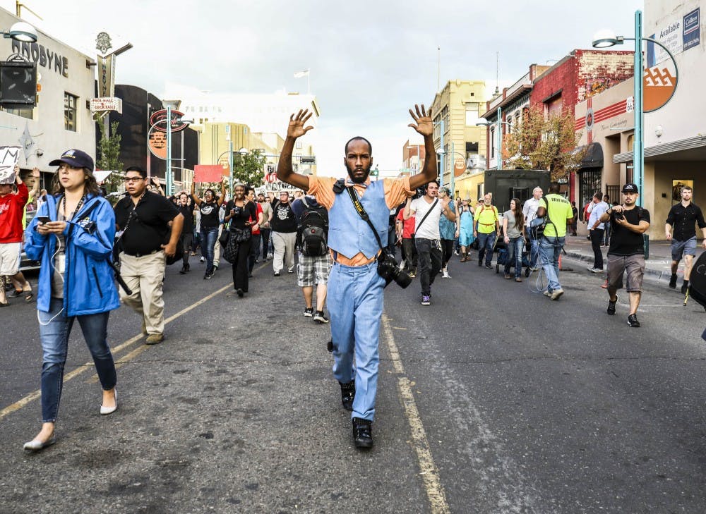 Arthur Bell raises his arms as protesters chant “hands up don’t shoot” during the Black Lives Matter March on Friday, Sept. 22, 2017. Participants marched through Downtown before stopping at the roundabout on 8th Street.&nbsp;