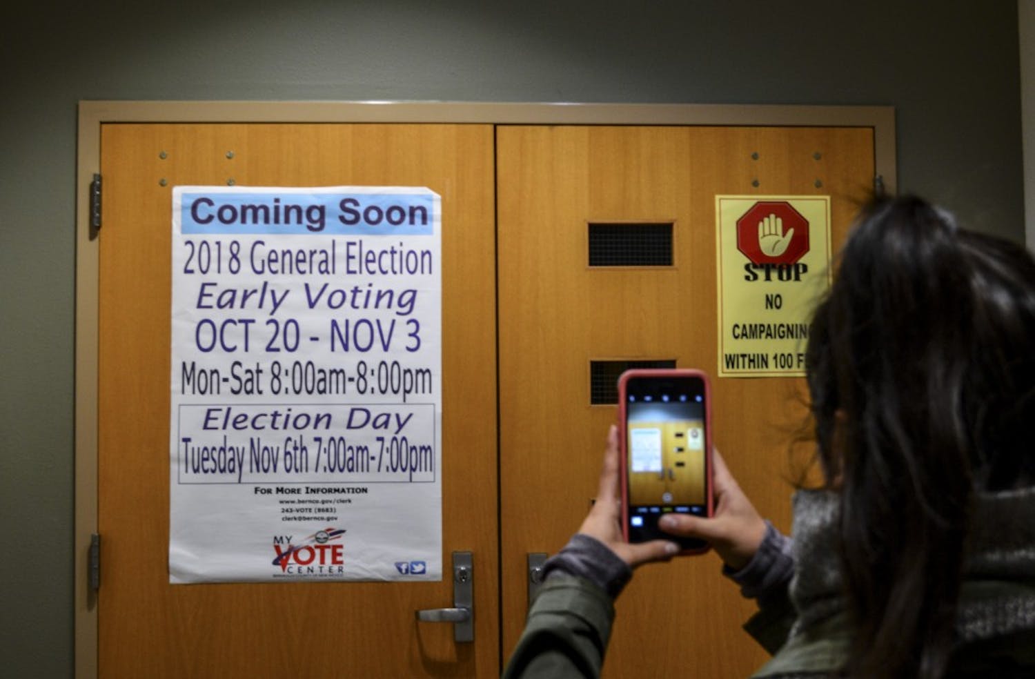 A student takes pictures of a sign regarding UNM’s early voting center.