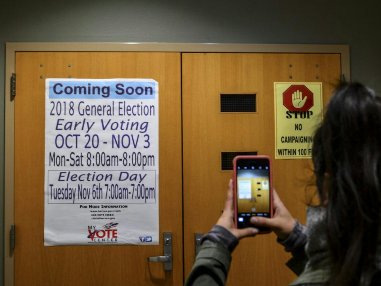 A student takes pictures of a sign regarding UNM’s early voting center.