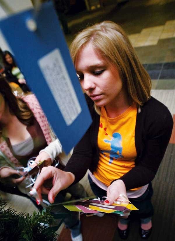 Student Hallee Kells hangs tags adorned with children's wish lists on the Community Experience Giving Tree in the SUB Atrium on Monday. 