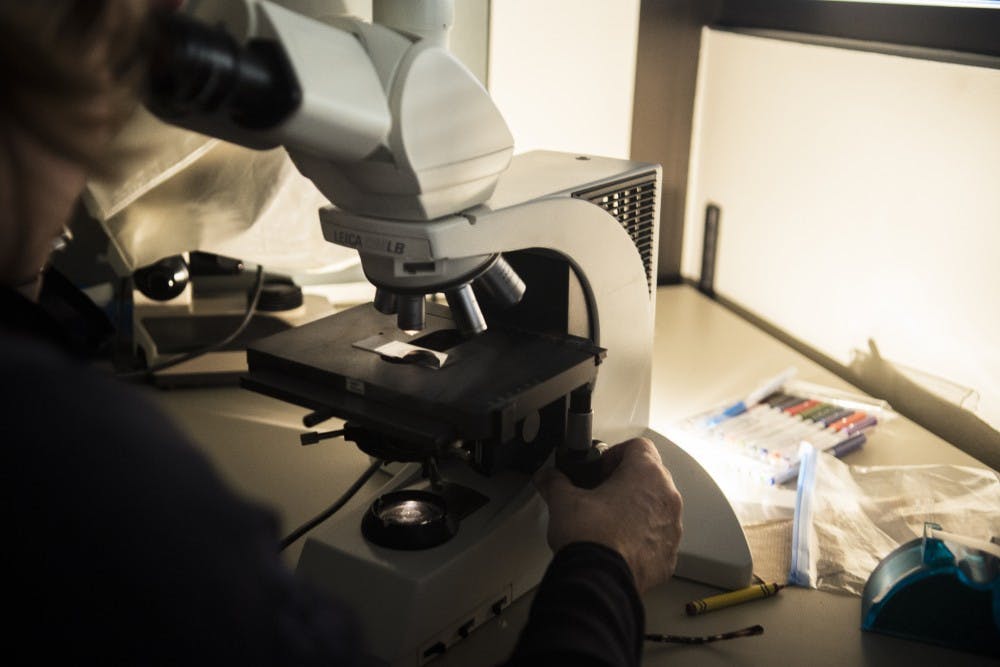 Cosette Wheeler looks at slides through a microscope Friday afternoon at the UNM Cancer Research Facility. Wheeler and her team run a laboratory on north campus that studies the&nbsp;Human Papillomavirus and how it interacts with cells.&nbsp;