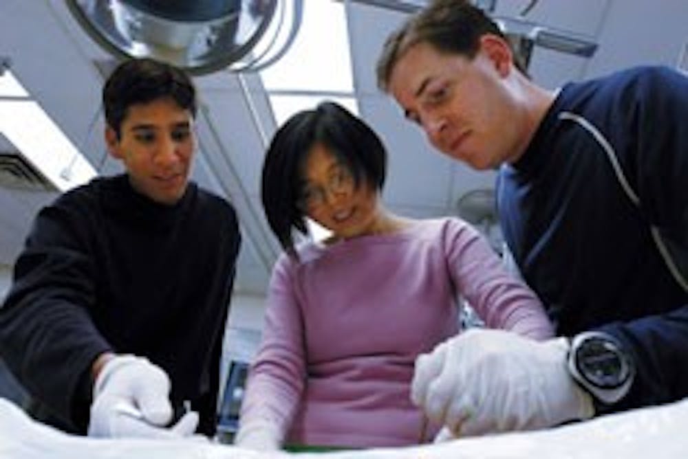 Third-year medical school students, from left, Michael Benavidez, Grace Xu and David Meredith, study a cadaver in their anatomy lab at UNM Hospital on Monday.