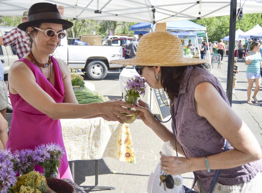 	Universal Herbs owner Allison Alterman shows a wild monarda to customer Karen Wood during the Los Ranchos Growers’ Market on Saturday morning. Alterman has been a vendor at the Growers’ Market for seven years.