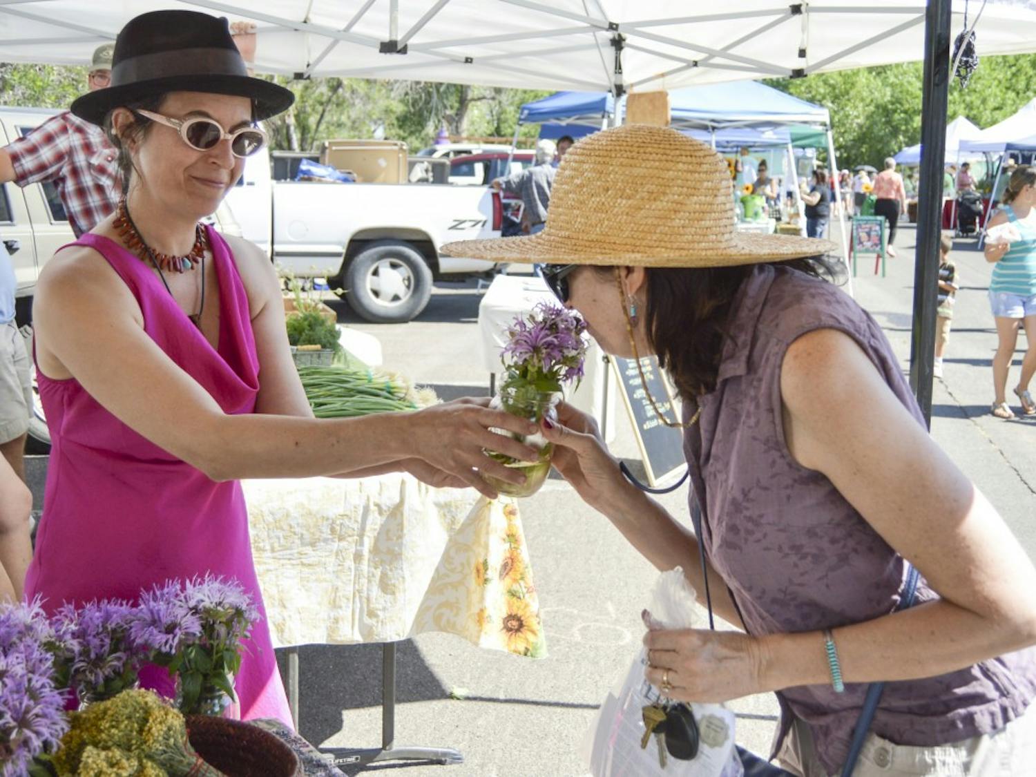 	Universal Herbs owner Allison Alterman shows a wild monarda to customer Karen Wood during the Los Ranchos Growers’ Market on Saturday morning. Alterman has been a vendor at the Growers’ Market for seven years.