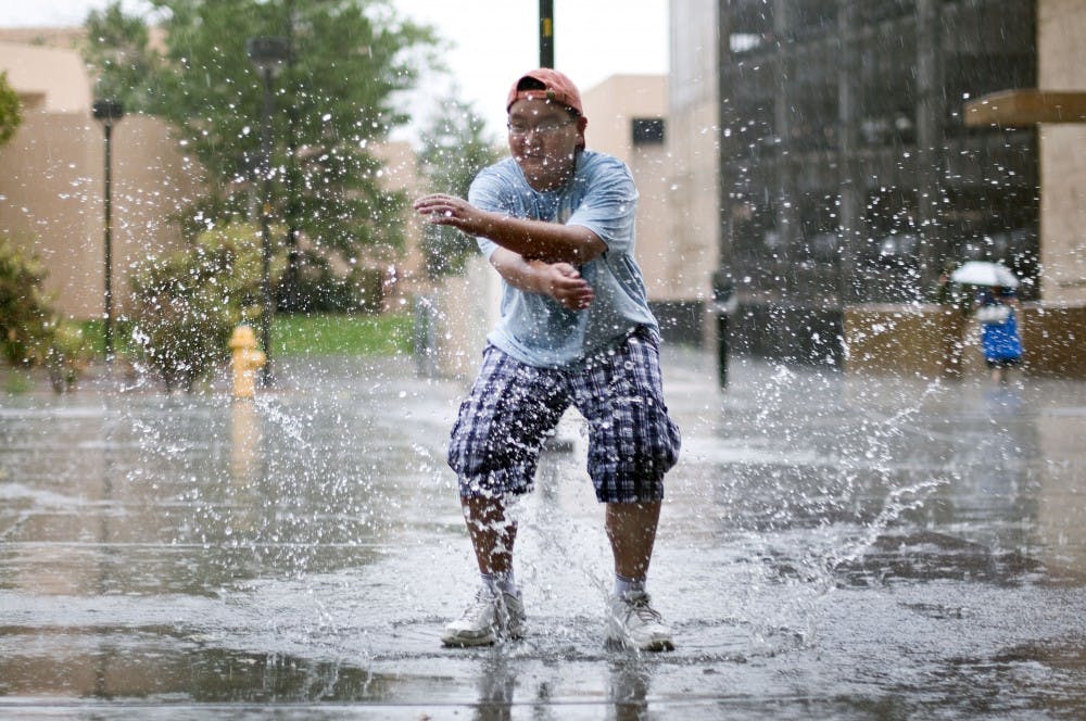 	Alan Duong, a seventh-grader at Albuquerque Academy, splashes in a puddle outside of Popejoy Hall on Thursday. Duong and other students visited campus for a photography class.