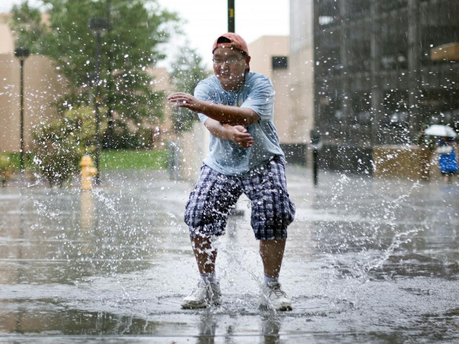 	Alan Duong, a seventh-grader at Albuquerque Academy, splashes in a puddle outside of Popejoy Hall on Thursday. Duong and other students visited campus for a photography class.