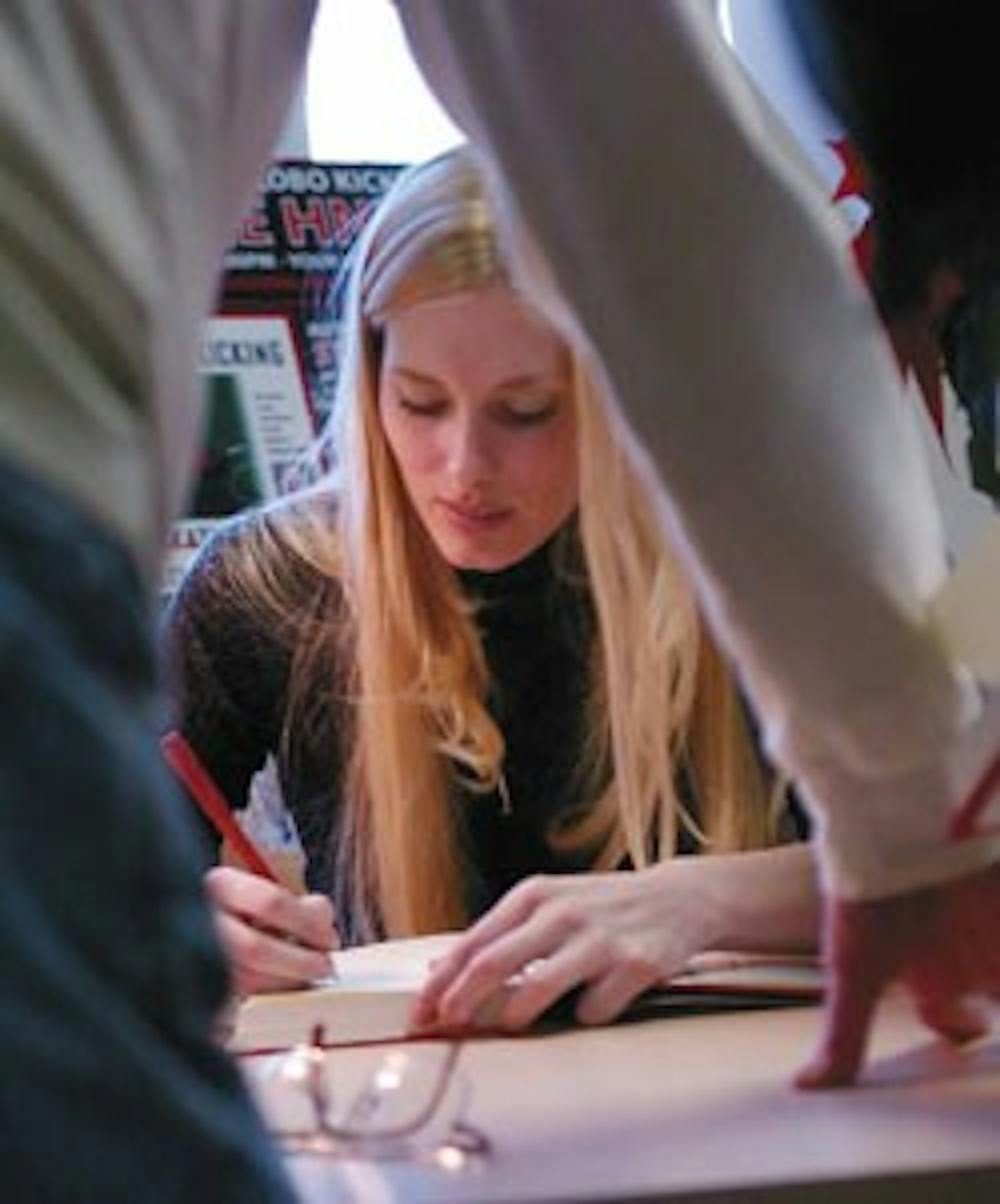 Former UNM kicker Katie Hnida signs a copy of her book, Still Kicking: My Journey as the First Woman to Play Division I Football, for Dick Webb on Thursday at the Bookstore. 