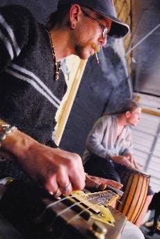 Instrument maker and musician Mike Rose, left, plays his homemade slide guitar while Mitchell Owen plays drums during a practice Tuesday at The Curio. 