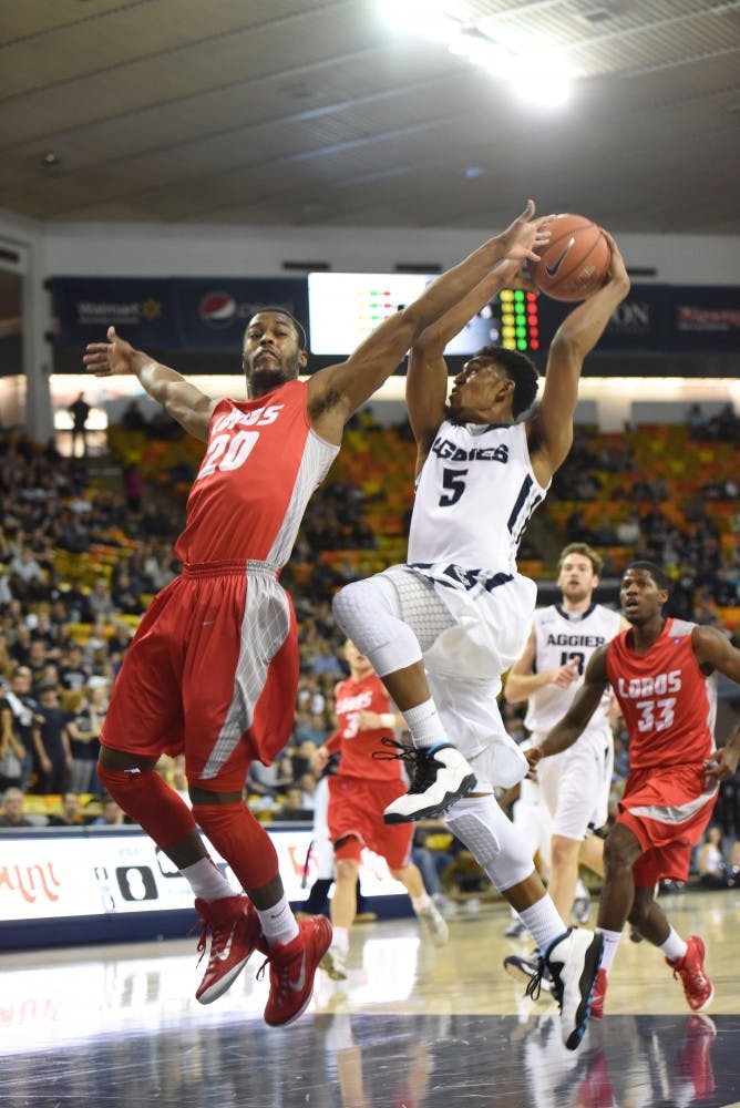 New Mexico guard Sam Logwood attempts to block Utah State guard Julion Pearre from scoring at the Dee Glen Smith Spectrum in Logan, Utah on Saturday. The Lobos defeated the Aggies 66-60.