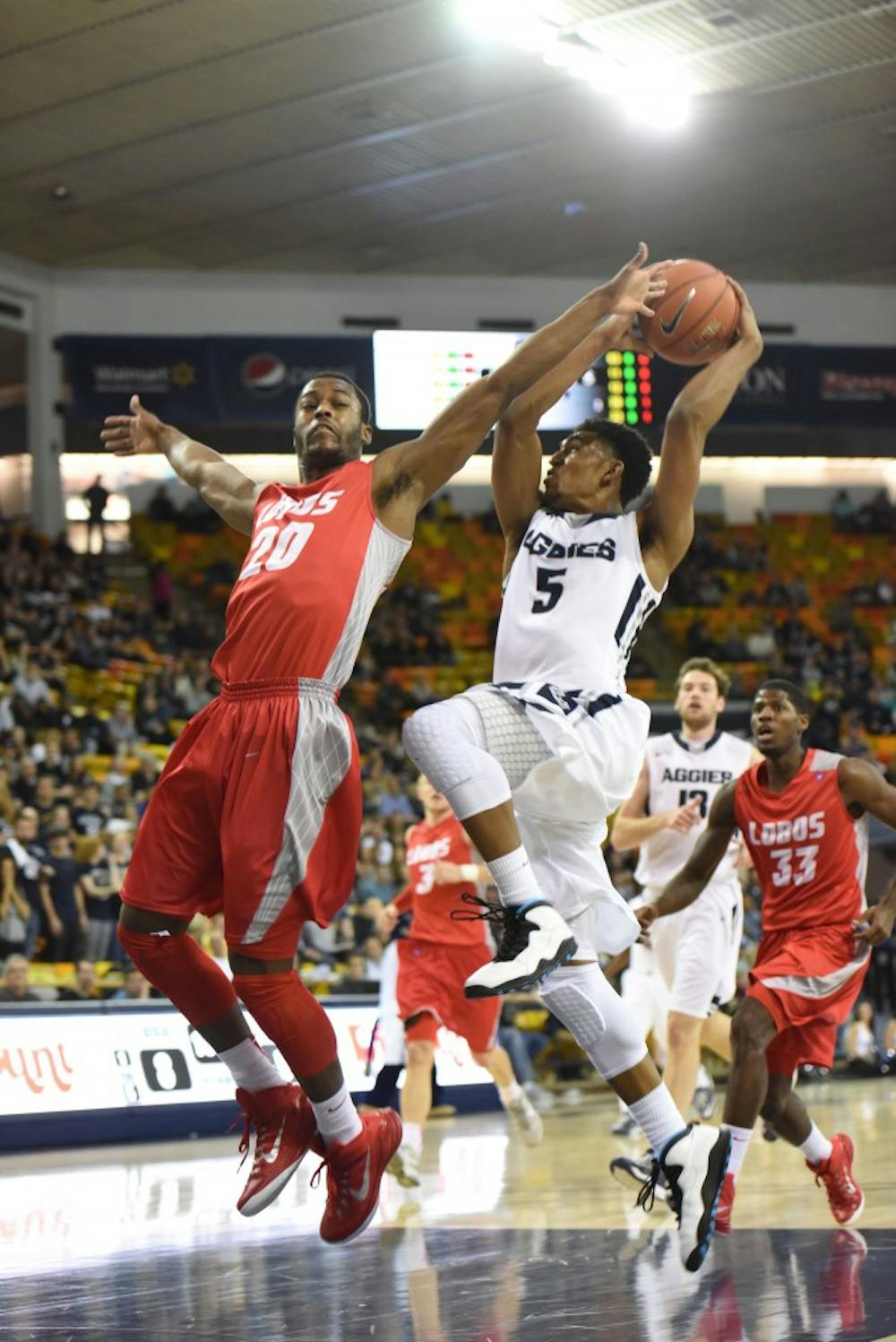 New Mexico guard Sam Logwood attempts to block Utah State guard Julion Pearre from scoring at the Dee Glen Smith Spectrum in Logan, Utah on Saturday. The Lobos defeated the Aggies 66-60.
