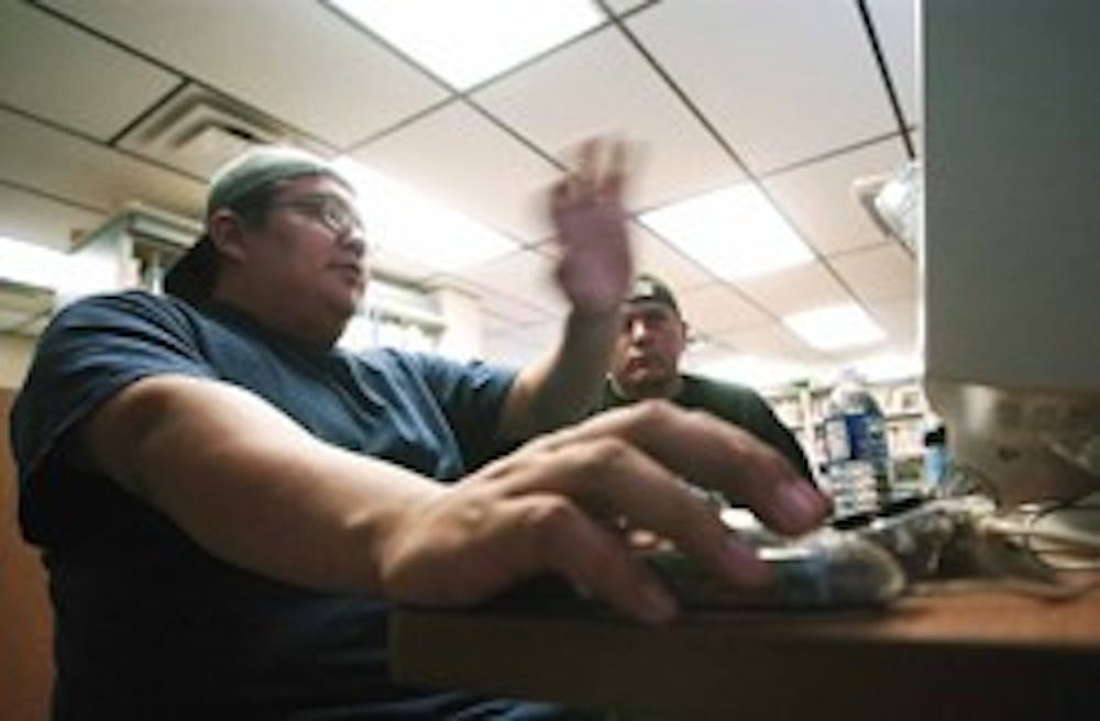 Ryan Brown, left, from the Navajo Times, lays out a page Friday with UNM student Patrick Willink for the Dawn of Nations Today, a newspaper that is part of a course called Native American Newspaper Publications.  