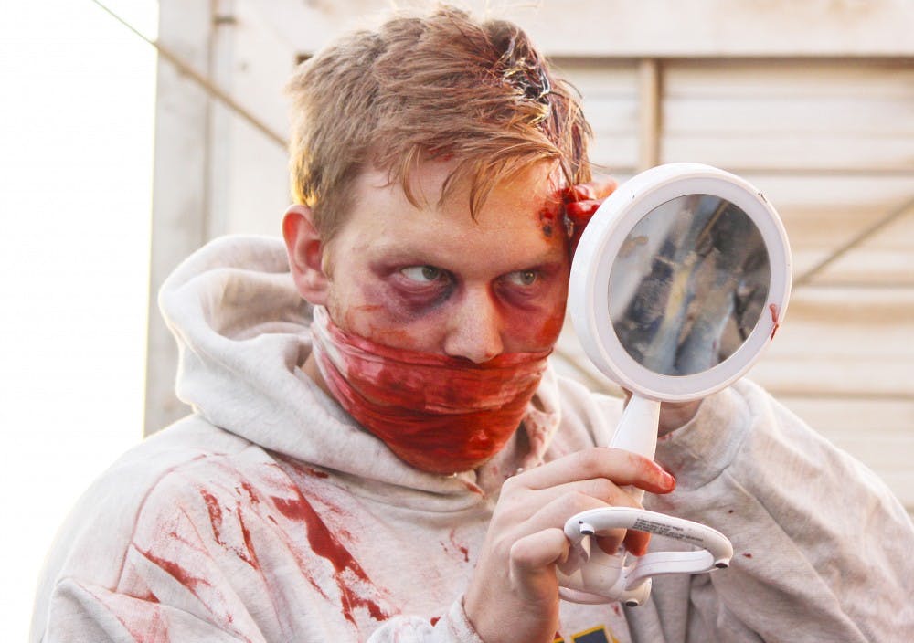 Patrick Gozur, a volunteer with the Rio Grande Community Farm, applies zombie makeup on Tuesday night for the farm’s haunted maze “Quarantine: Collapse.” Gozur is one of hundreds of people volunteering as zombies for the event. “Quarantine: Collapse” has its last official fright night on Nov. 1.