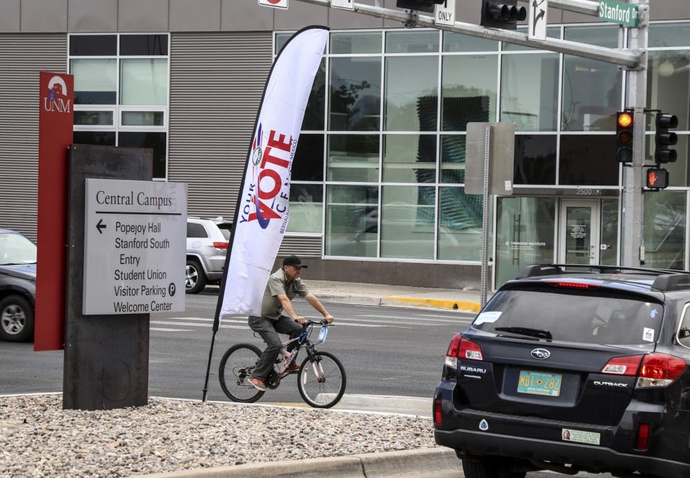 A man rides a bike by a voting location sign on Central and Stanford Dr. on June 3, 2018. Primary voting takes place on June 5.