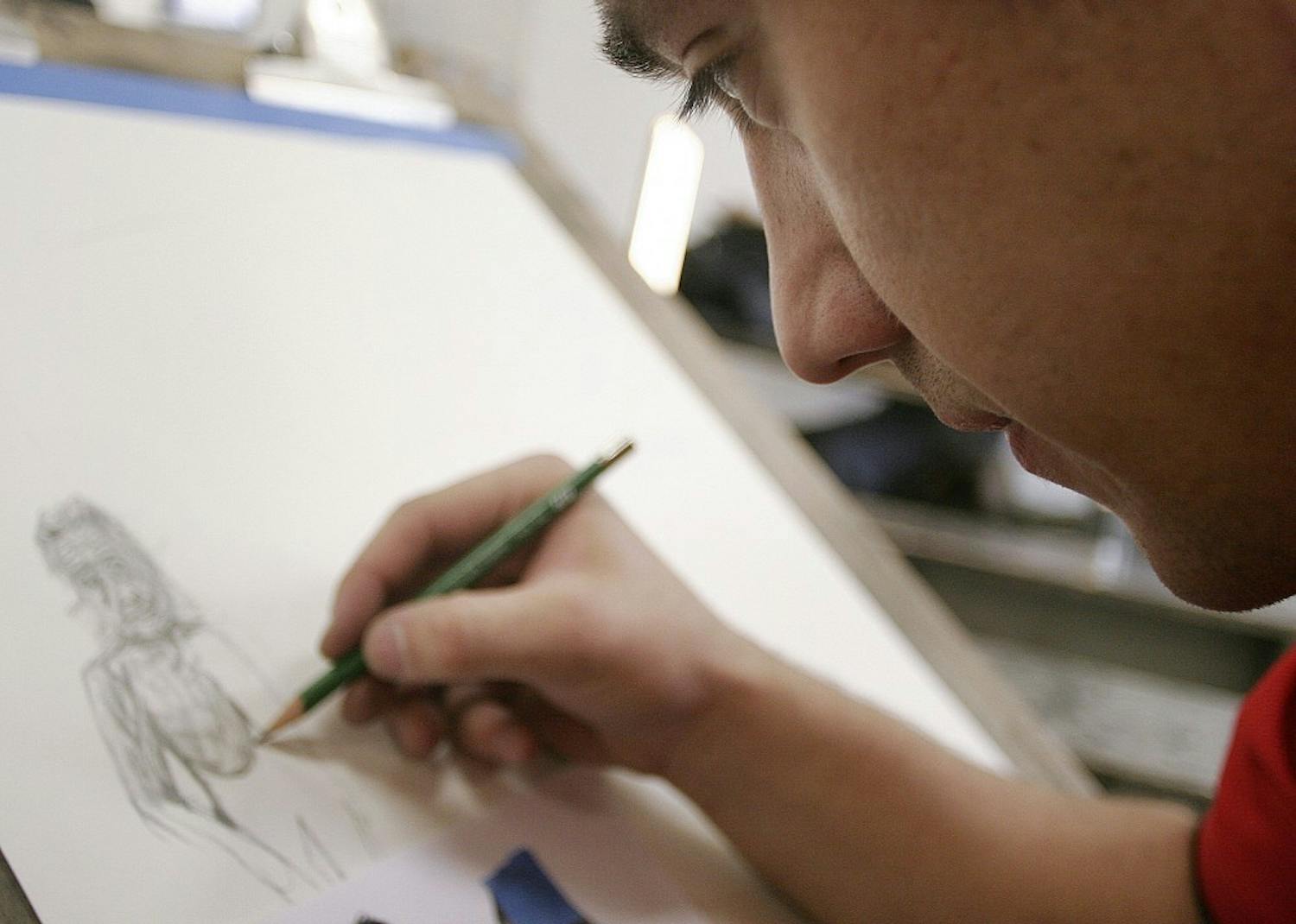	Student Mario Villagomez works on his drawing project in the Art Building on Monday. The Art Building studios are open from 7 a.m. to 11 p.m. every day, but security only began enforcing the closing policy a week ago. Some art students say the building should stay open so they can work later.