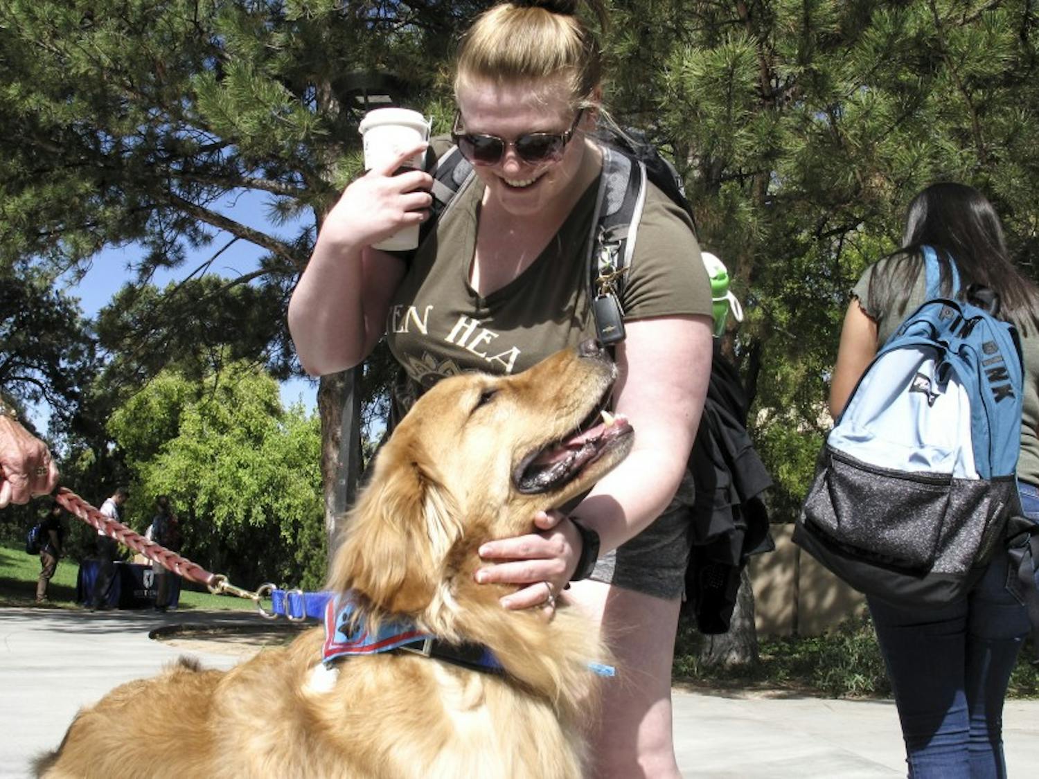 A UNM stops to pet a dog on her way to class.