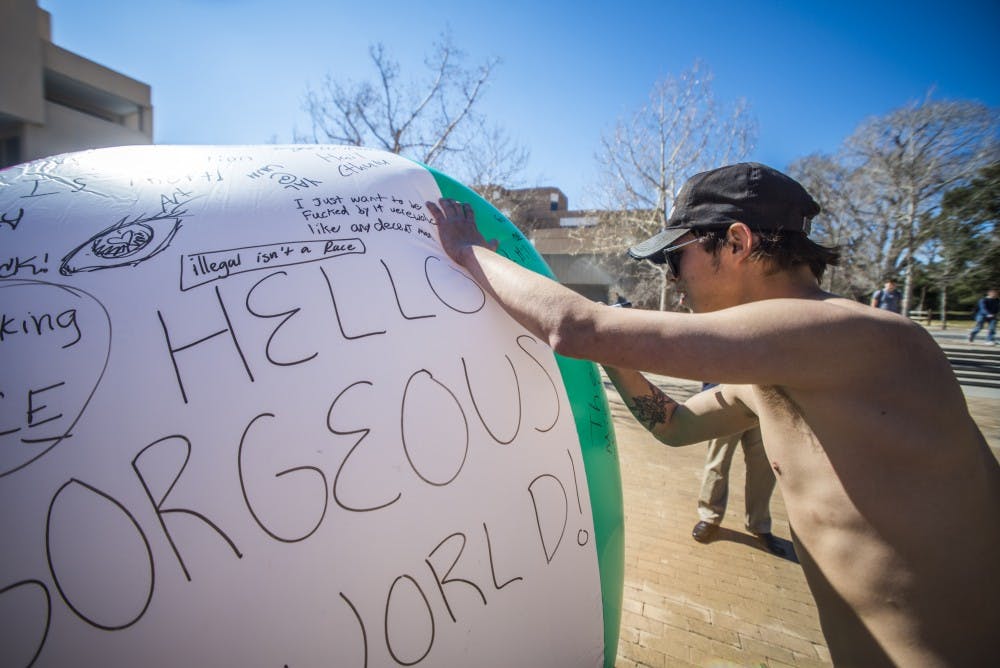 Adrian Sifuentez writes on a large beach ball Wednesday, Feb. 15, 2017 at UNM's Smith Plaza. The ball was titled a "Free Speech" ball intended to let people express their free speech rights by writing whatever they please.&nbsp;