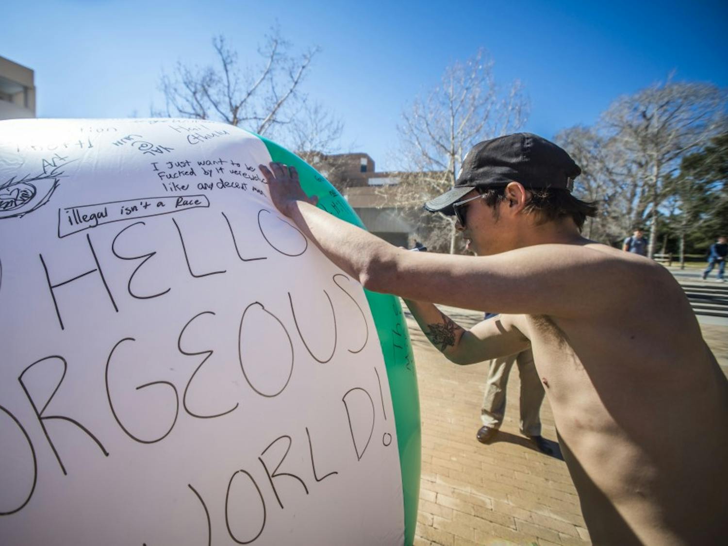 Adrian Sifuentez writes on a large beach ball Wednesday, Feb. 15, 2017 at UNM's Smith Plaza. The ball was titled a "Free Speech" ball intended to let people express their free speech rights by writing whatever they please. 