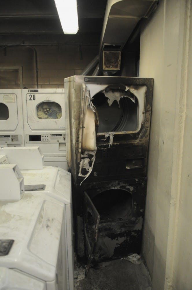 	Fire-damaged dryers sit in the laundry room of Hokona Hall on Friday. Smoke from the fire that started Friday morning entered the building’s ventilation system and circulated throughout the dorm.