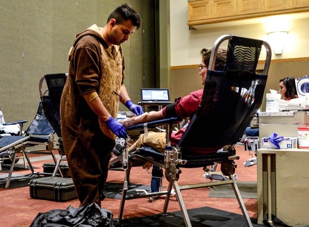 Jeremiah Ramirez adjusts the phlebotomy tube on a student at an ASUNM Community Experience Halloween Blood Drive in one of the SUB Ballrooms on Oct. 31, 2017.