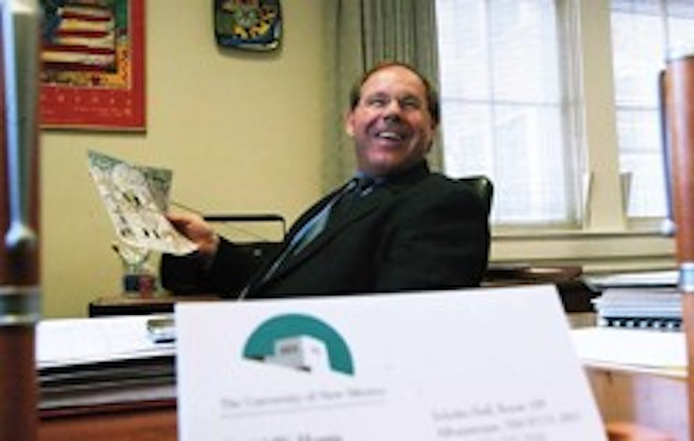 UNM's acting President David Harris laughs at an editorial cartoon in his office in Scholes Hall on Tuesday.