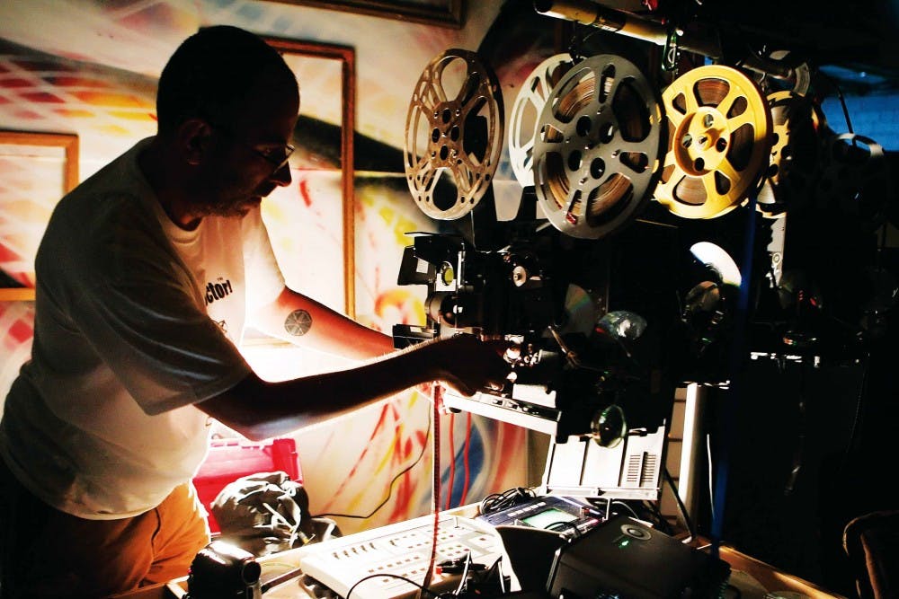Projexorcism performance group member "Isen Hour" sets up projectors before performing at The Curio on July 6. 